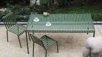 A minimalist dark green slatted metal outdoor table and chairs