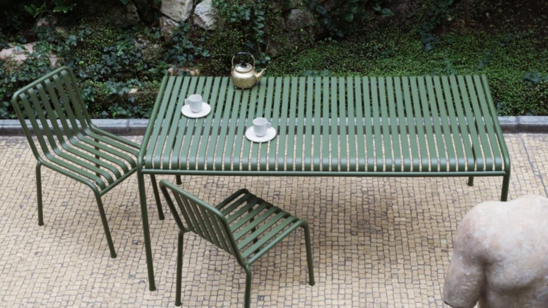 A minimalist dark green slatted metal outdoor table and chairs