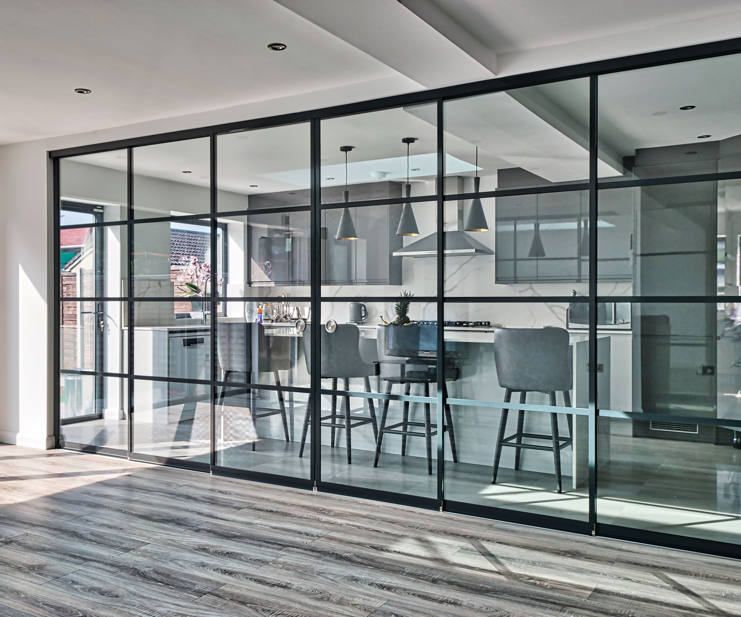 open-plan kitchen and living space divided by a contemporary glazed internal partition wall