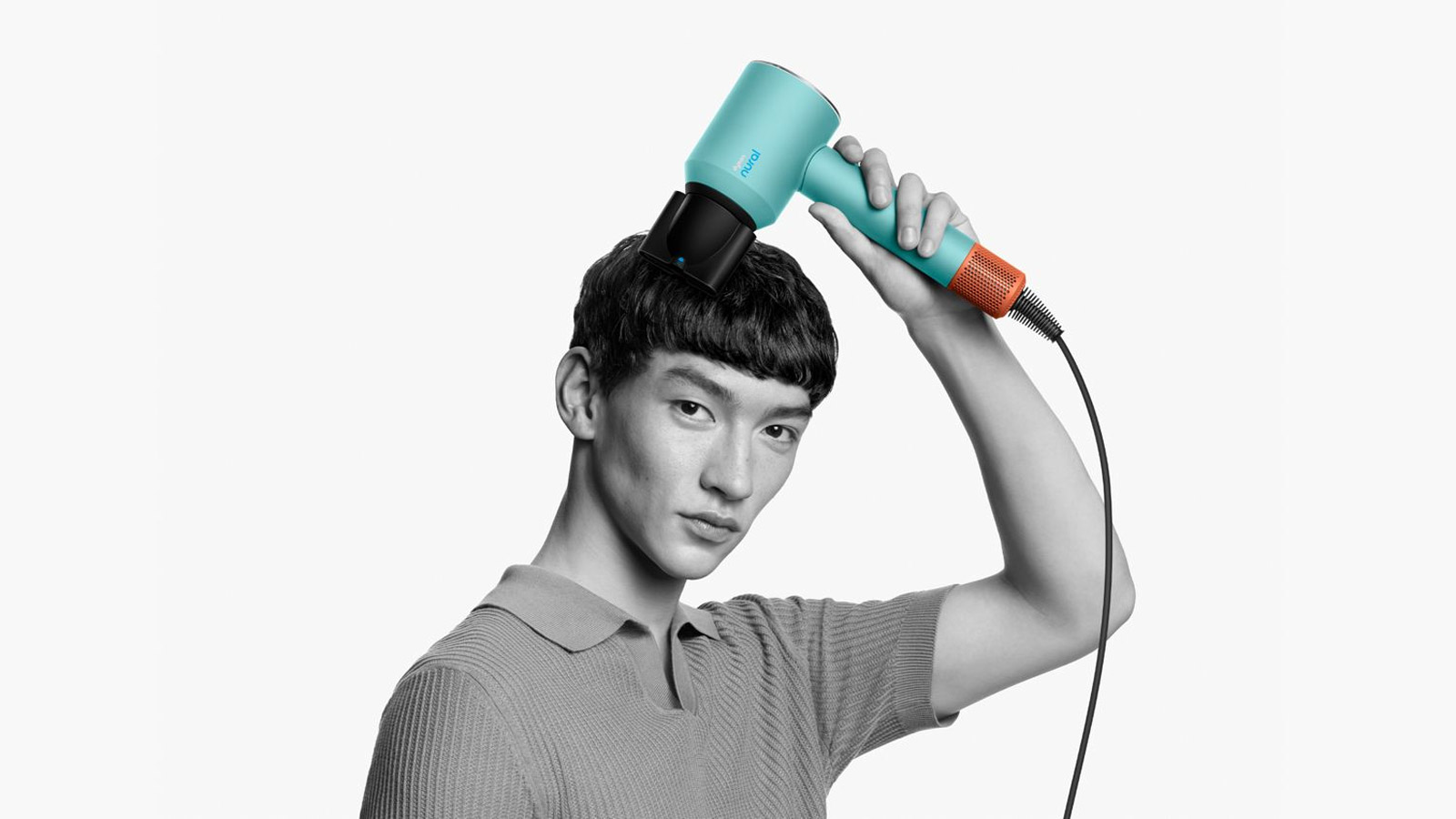 A man with short hair using a Dyson Supersonic Nural hair dryer