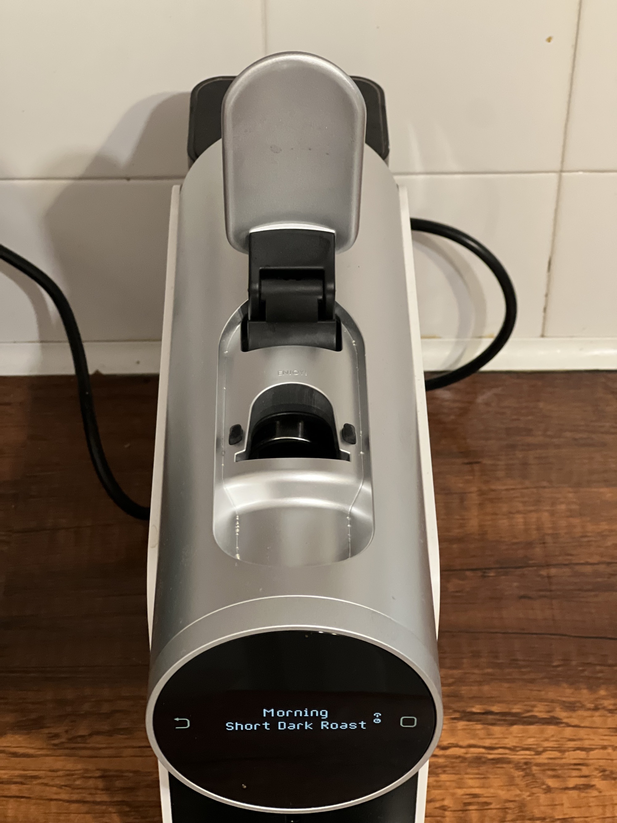 Close-up image of a silver coffee pod machine from above with the slot to put the pods in open.