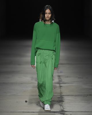 Woman model in green outfit walking on runway at Milan Fashion Week