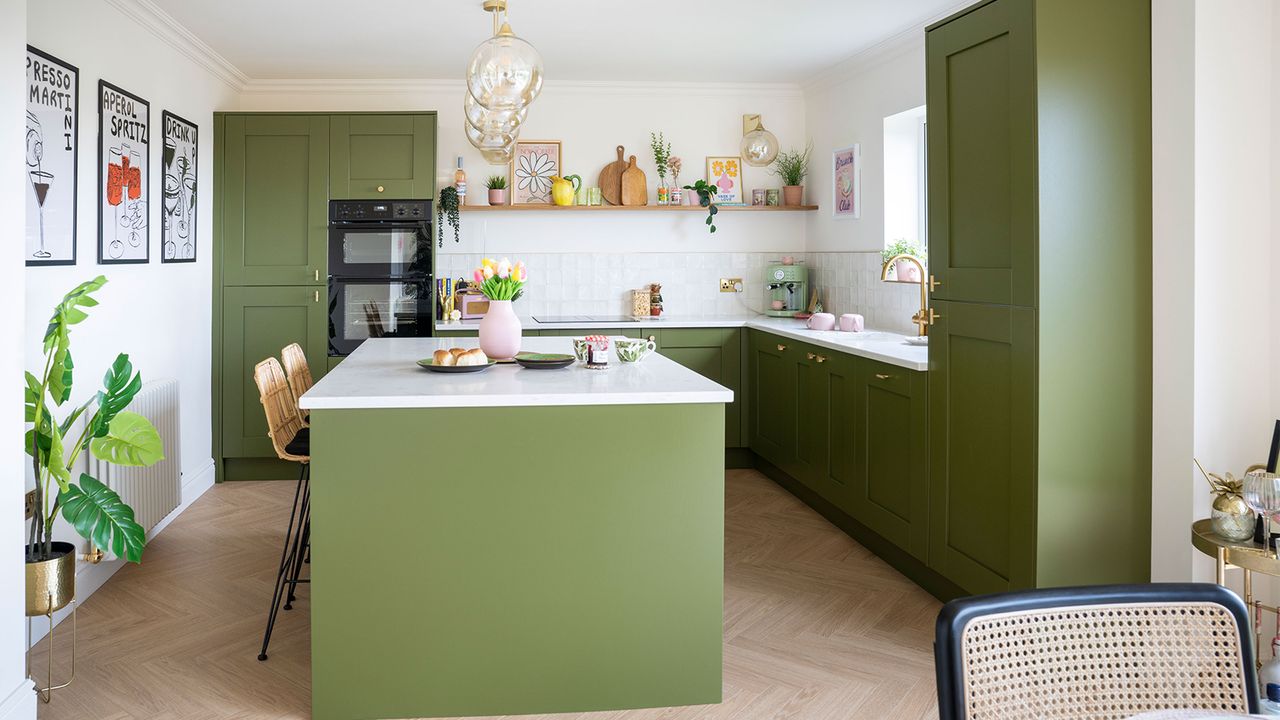 Green kitchen with central island and glass pendant lights