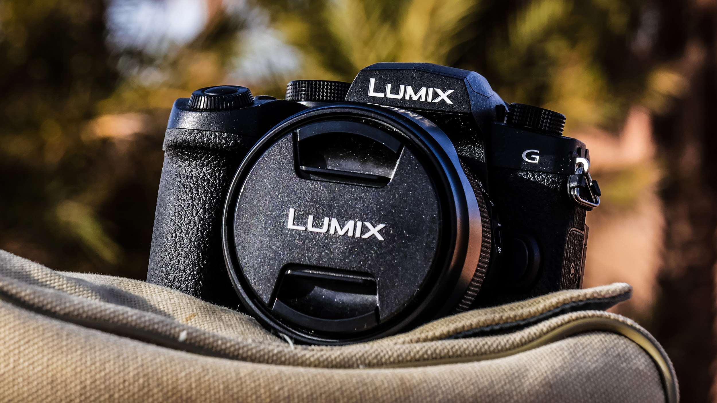 Panasonic Lumix G97 with lens attached, resting on a satchel outdoors