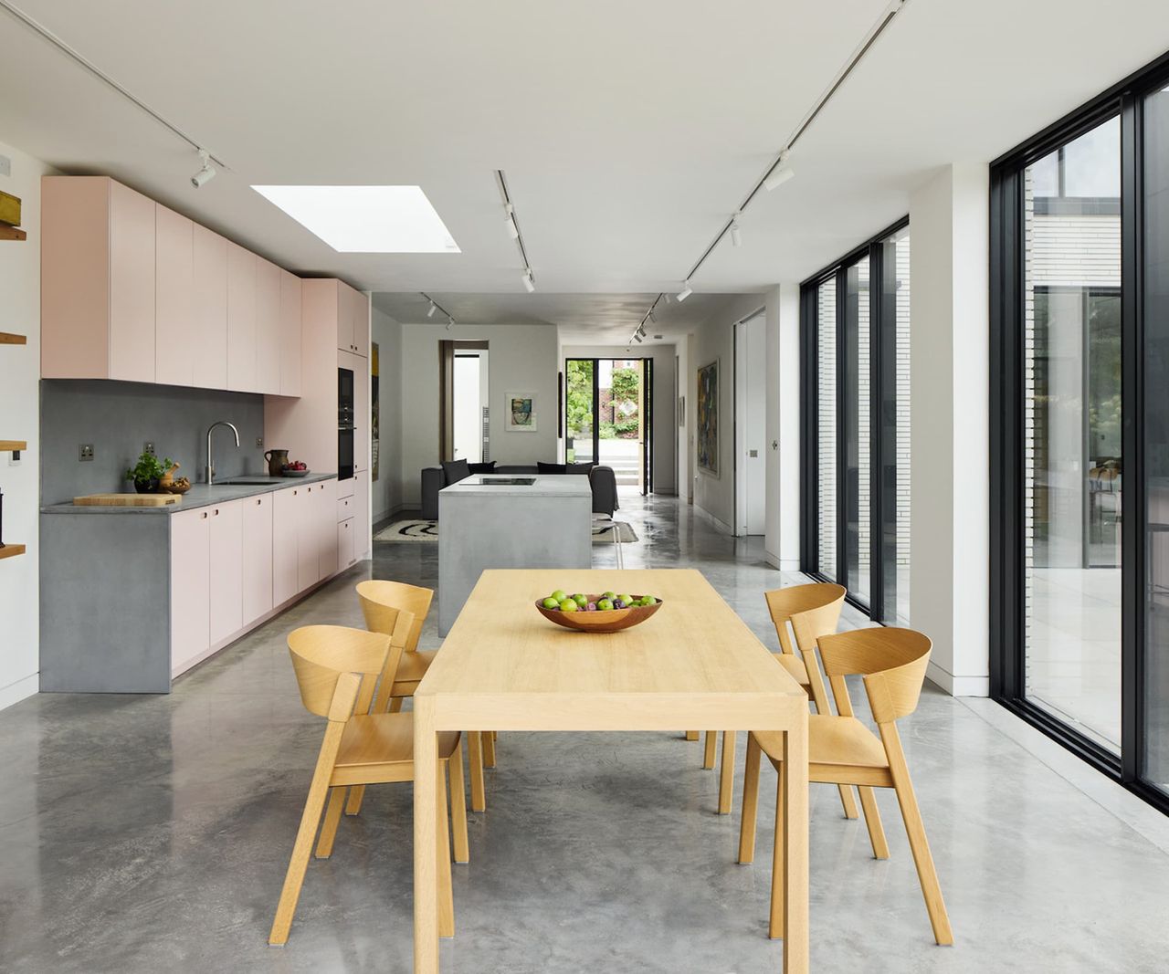 An open-plan kitchen with gloss grey flooring and pink cabinet