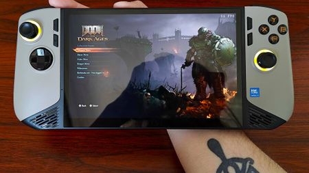 Hand holding MSI Claw 8 AI+ with DOOM: The Dark Ages main menu on screen