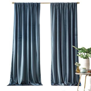 Blue velvet curtains next to a small table with houseplants in vases