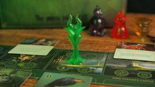 The Maleficent mover, board, and cards from Disney Villainous on a wooden table