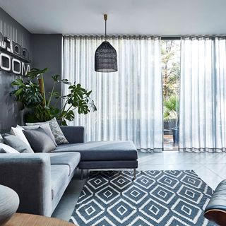 living room with teal grey colour wall and sofa set with cushions and smoke wave curtains