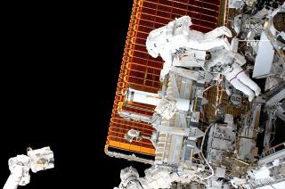 two nasa astronaut spacewalking outside the international space station, with the darkness of space in the background