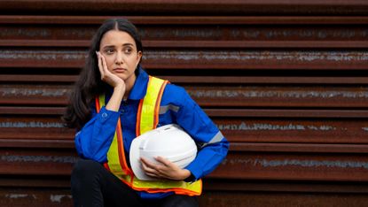 fed up blue-collar worker sitting at an industrial site