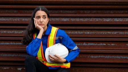 fed up blue-collar worker sitting at an industrial site
