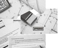 A close-up of planning documents, including an 'APPROVED' stamp, a calculator, and architectural plans, illustrating the planning permission process.