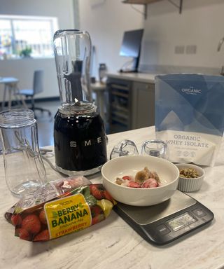 A black Smeg PBF01 personal blender with organic whey isolate, frozen bananas and berries and nut granola