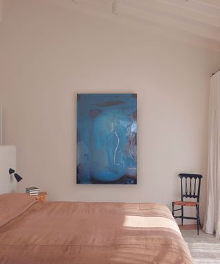 bedroom with pink linen sheets and blue artwork on wall
