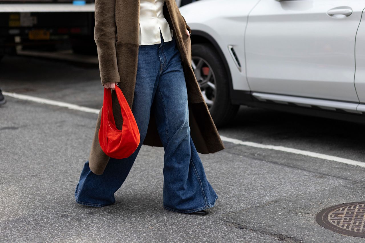 attendee at new york fashion week fall winter 2024 wearing baggy jeans, brown coat, and red bag