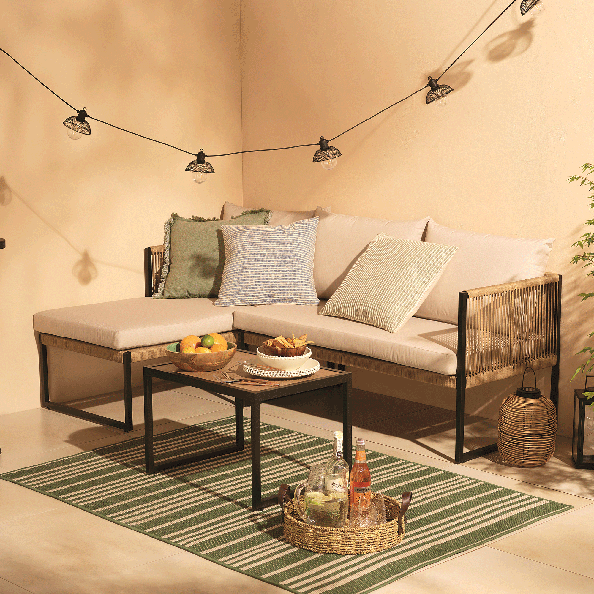 Tesco garden furniture corner sofa with blue and green cushions against a neutral backdrop 