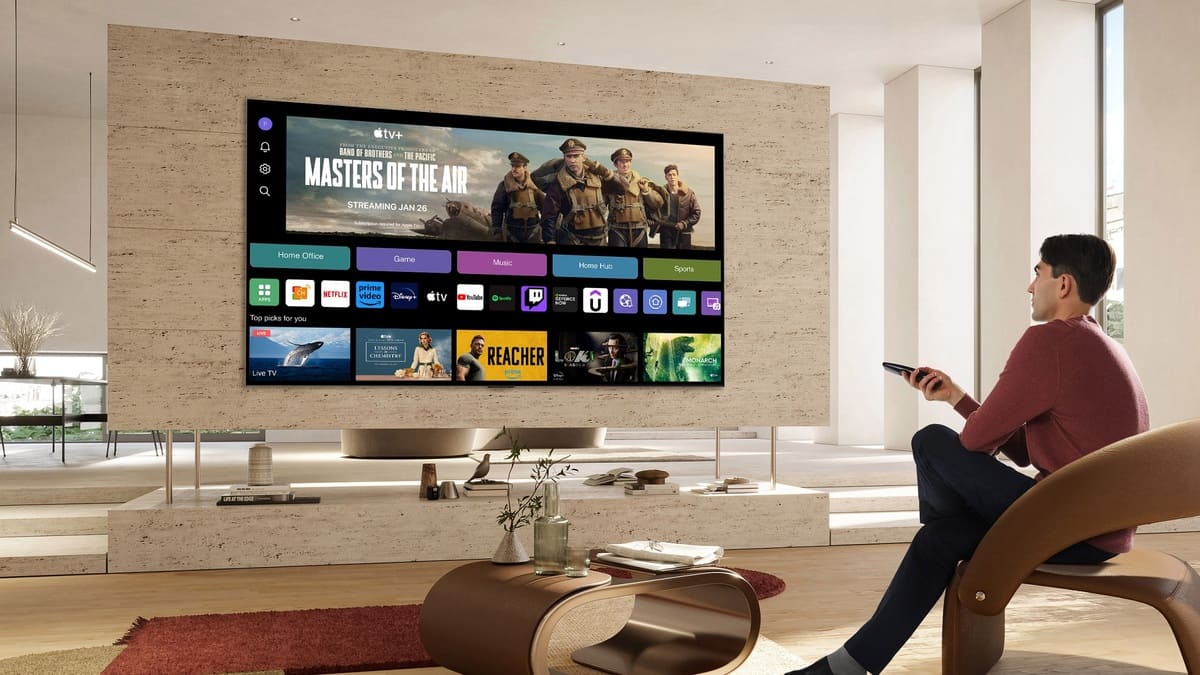 Rendered image of LG webOS 25 on a big wall mounted TV in an expensive, neutrally decorated apartment with a young man looking at the tv