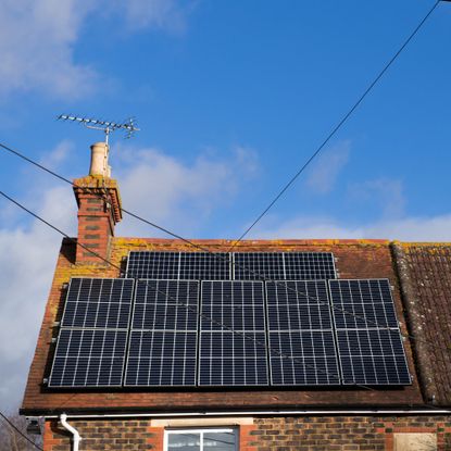 Solar panels on the pitched roof of a brick semi-detached cottage