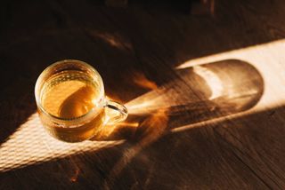 A glass mug of herbal tea on a wooden surface.