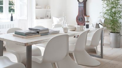 All white dining room with statement chair and vintage clock