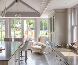 orangery kitchen extension with rooflight featuring blinds above kitchen with stone floor and cream shaker units