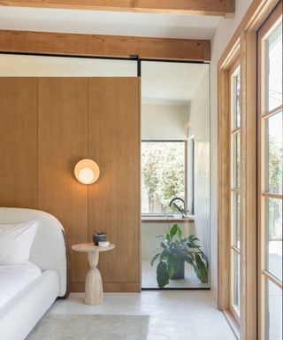 Japandi bedroom with blonde wood walls and a low boucle bed