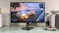 AOC Agon Pro AG276FK gaming monitor on a desk, showing Cyberpunk 2077 on screen