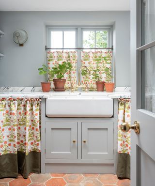 grey shaker kitchen with floral kitchen curtains in place of cabinets and blinds