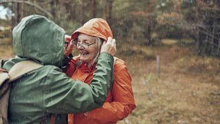 A hiker adjusts her companions hood as they hike in the rain