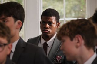 Roddy (David Olaniregun) stands in his school uniform surrounded by fellow pupils, with a worried look on his face