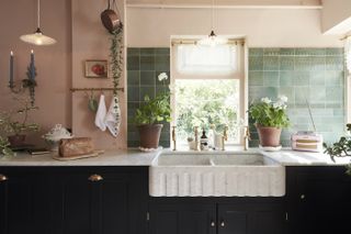 Navy kitchen cabinets with a marble worktop and sink plus green zellige tiles