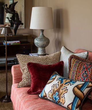 pink linen couch sofa styled with 5 different pillows including a leopard print, red velvet, and patterned pillow covers