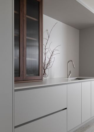 A minimalist style kitchen with contrasting dark brown fluted glass kitchen cabinets.