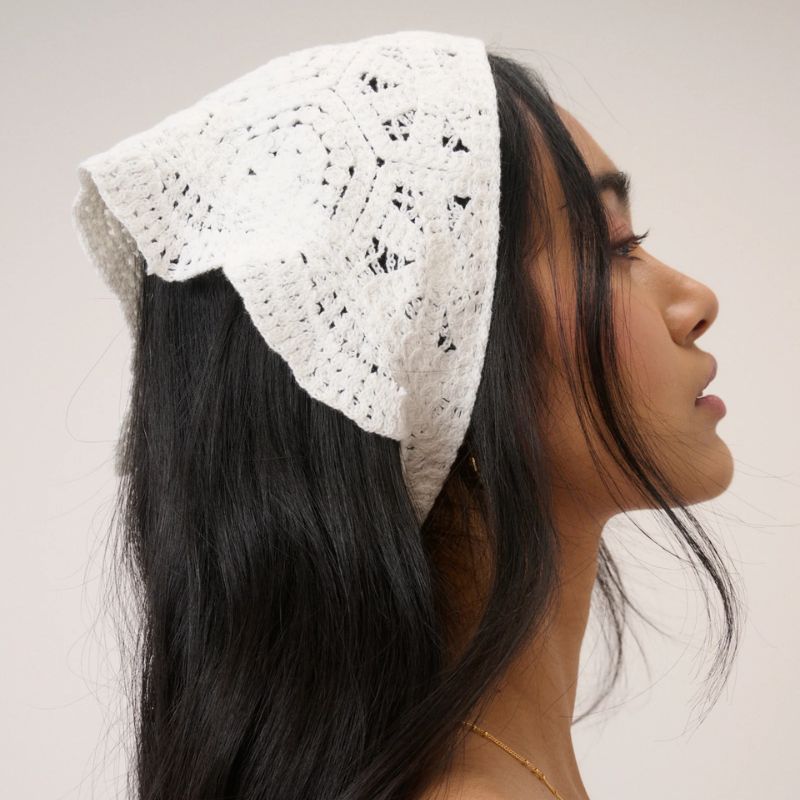 A woman wears a cream crochet head scarf