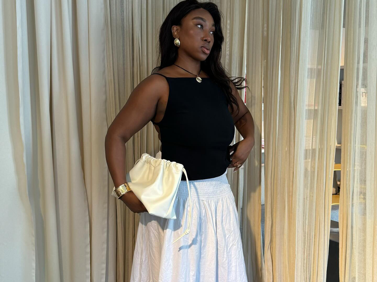 Influencer @nnennaechem wears a white long skirt, a black top, and a necklace.