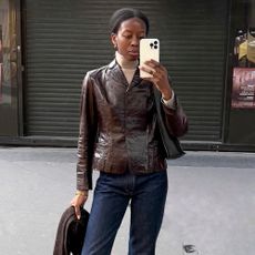 Influencer wears a brown leather jacket.