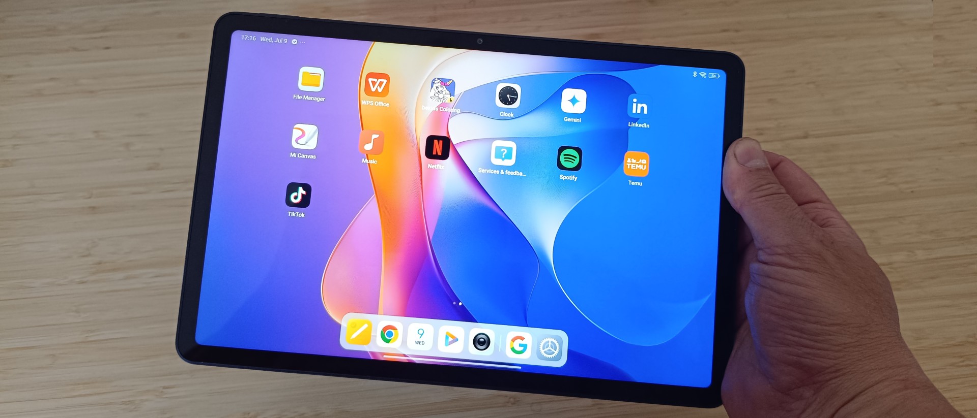Hand holding Redmi Pad 2 tablet over desk