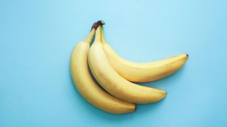 How to get rid of a headache fast illustrated by a bunch of bananas on a blue background as they are just one of the many foods that can trigger headaches so should be avoided as natural headache remedies