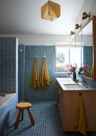 a bathroom with blue tiles and yellow towels hung on the wall