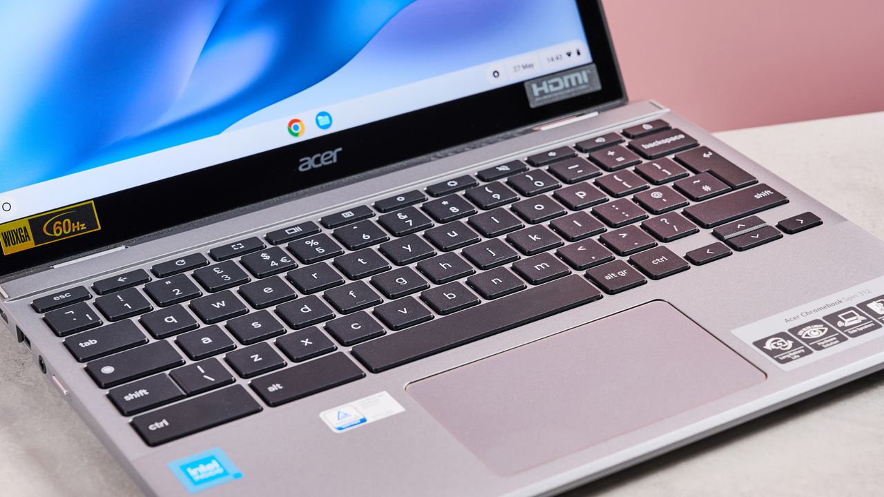 Close-up of keyboard and touchpad on Acer Chromebook Spin 312, on desk with pink background