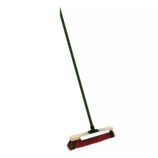 Broom with a black handle and red bristles with a metal scraper on the wooden head of the broom