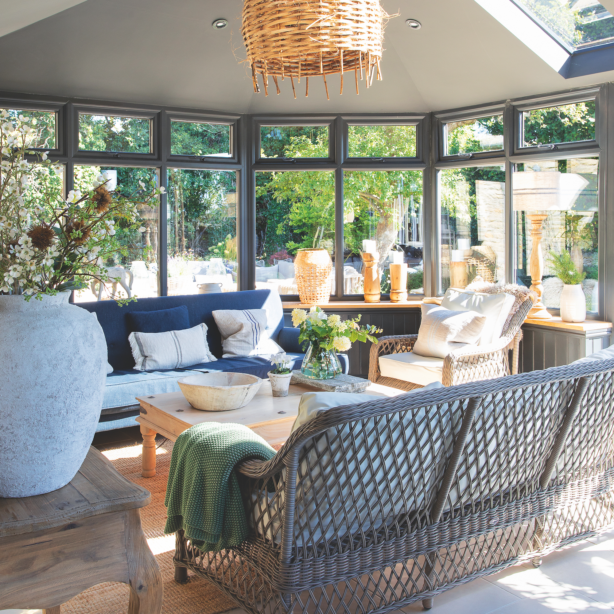 garden room with grey rattan sofa, blue sofa, wicker pendant shade and large pot