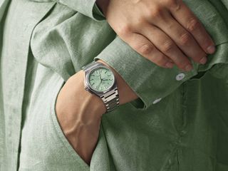 green-dial watch with steel bracelet on wrist