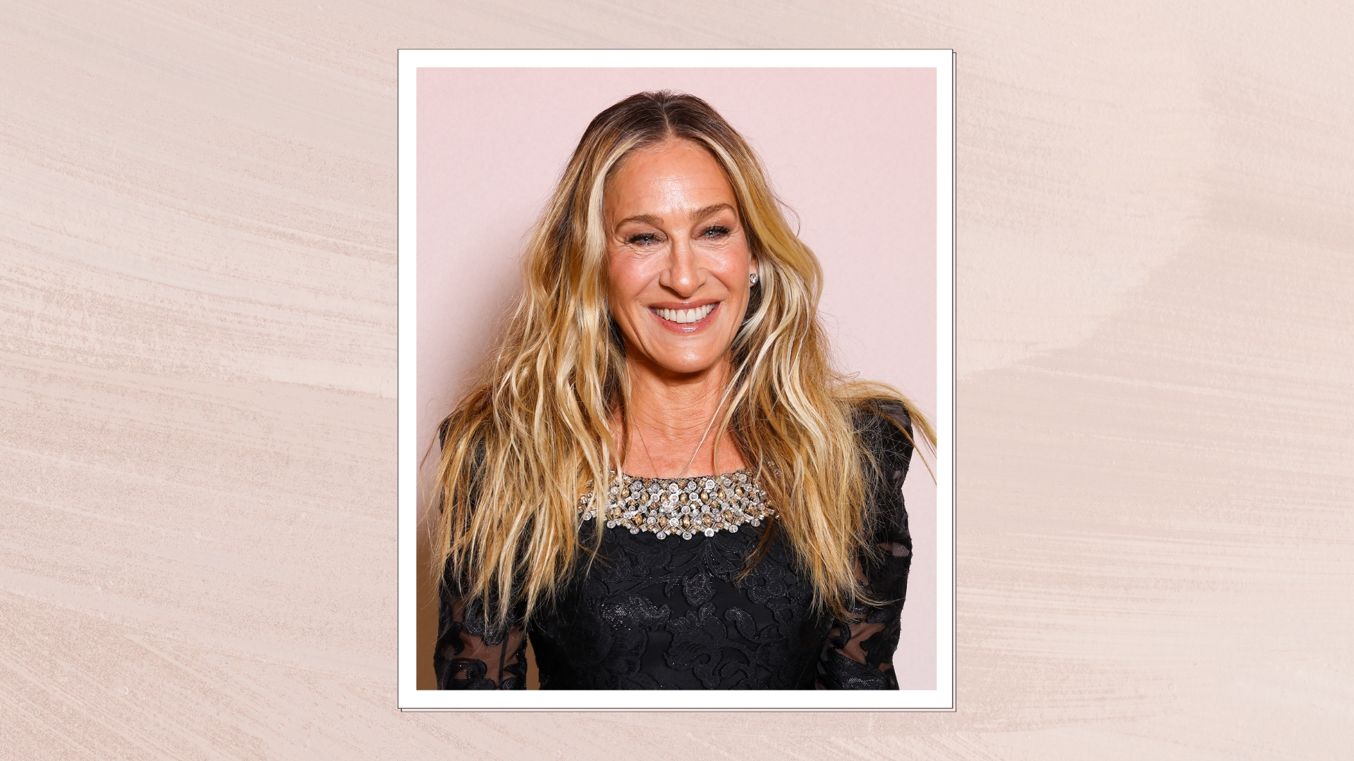 Sarah Jessica Parker is pictured in front of a pastel pink backdrop, with her hair in waves and wearing a black lace dress during the "And Just Like That…" Season Three Photocall at Hotel Napoleon on May 29, 2025 in Paris, France/ in a pastel pink watercolour paint-style template