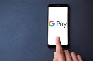 Google Pay logo on a smartphone with a hand hovering above