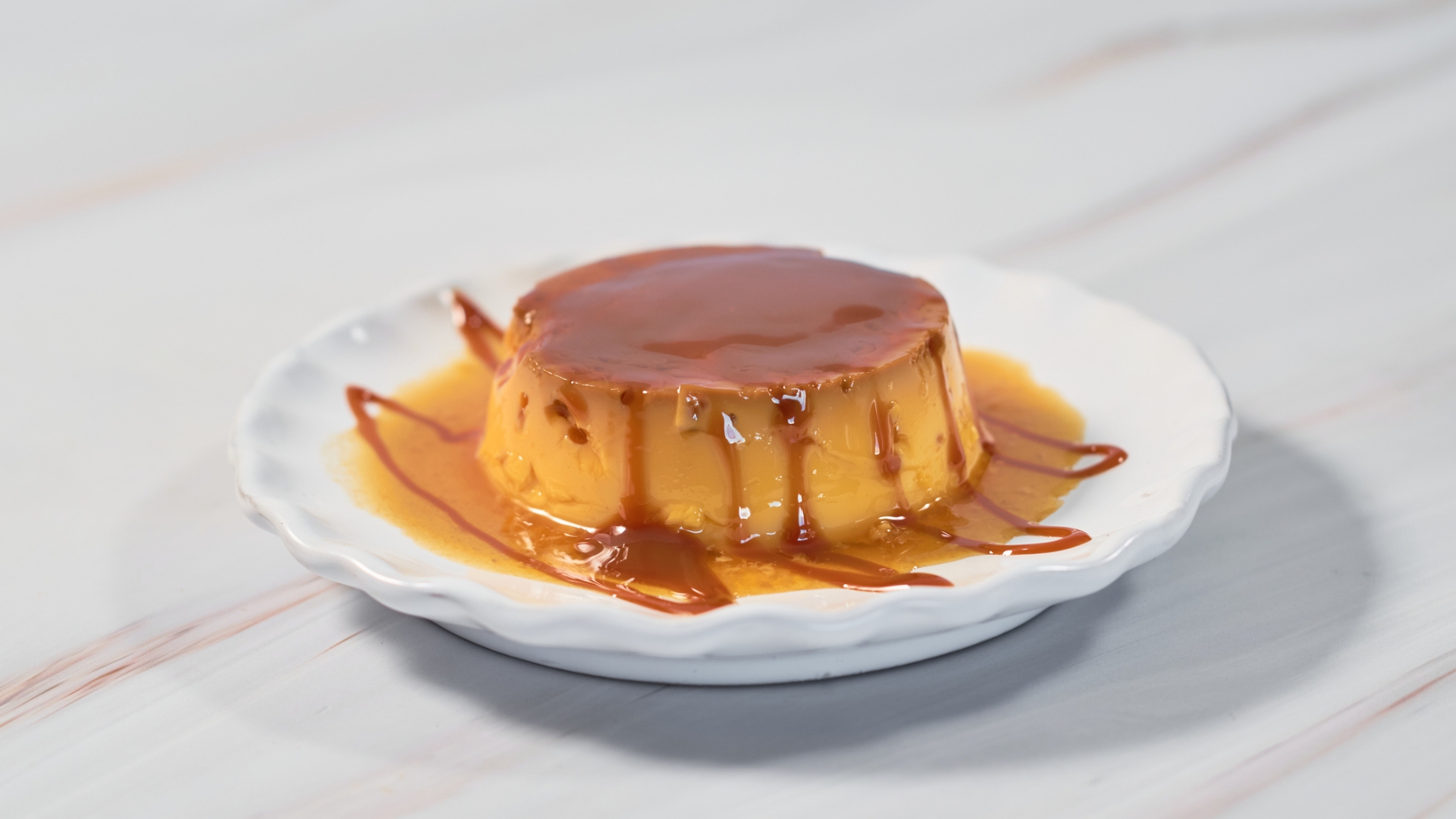 A caramel topped flan on a white plate