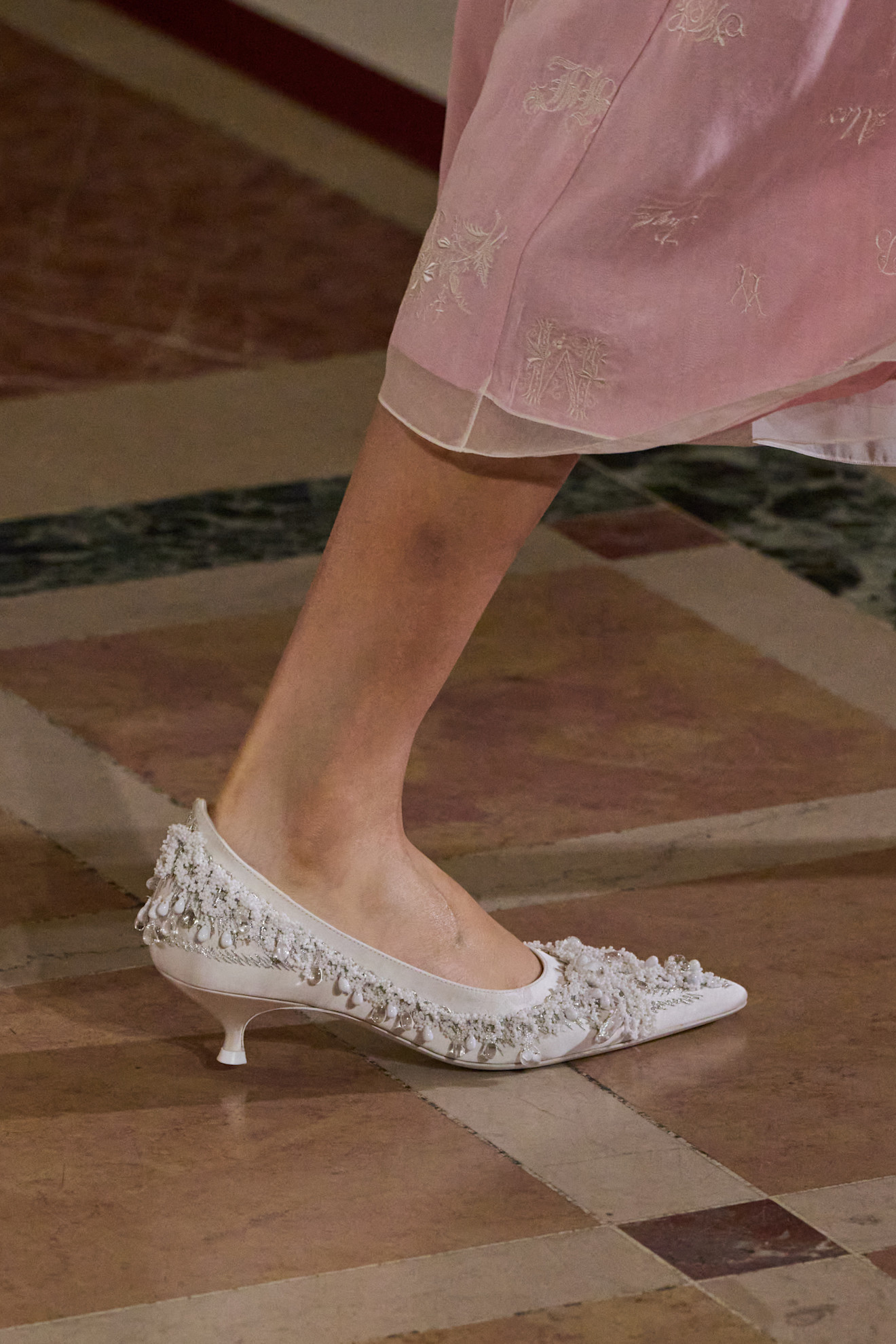 A Tory Burch model at the S/S 26 show wearing white beaded kitten heels.