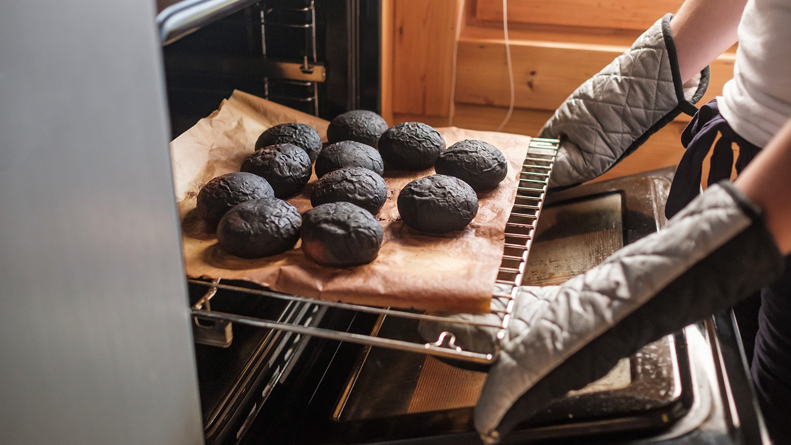 burnt muffins being taken out of an oven