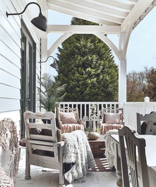 White porch, wooden chairs, blankets